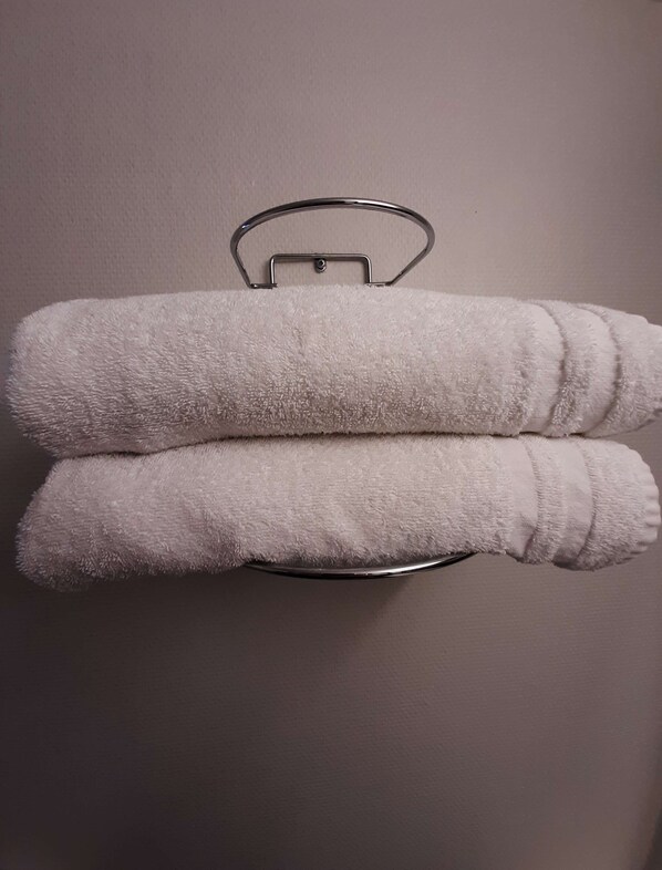 Two white towels folded and hung on a metal towel rack against a plain wall. - Premiere Classe Mâcon Sud (Chaintre)