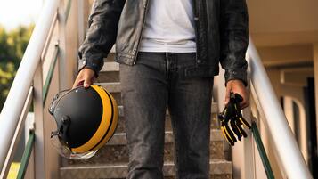 A person descending a staircase, holding a helmet and gloves.