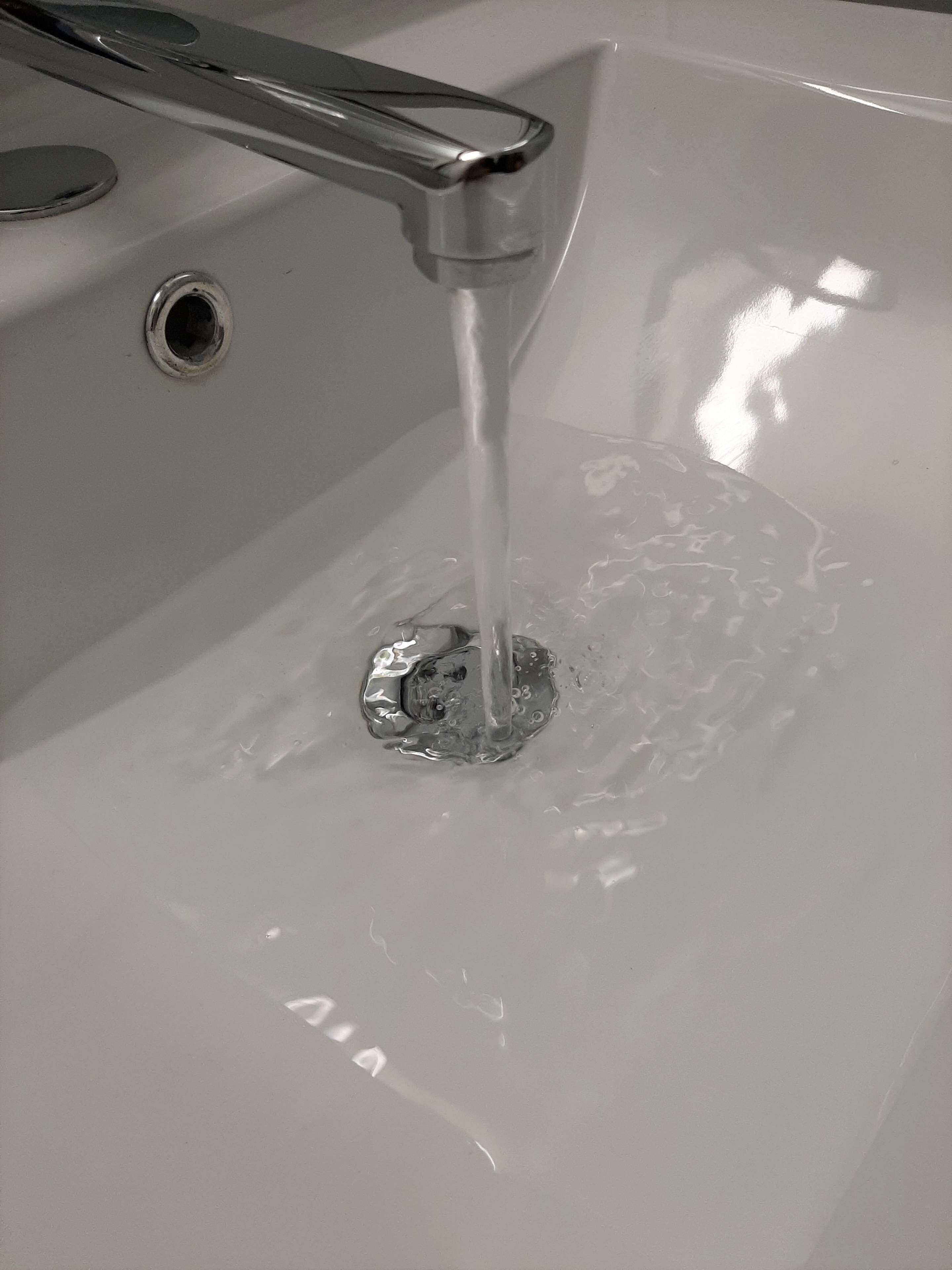 Un lavabo con agua corriendo, desagüe y grifo.