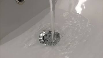 Un lavabo con agua corriendo, desagüe y grifo.