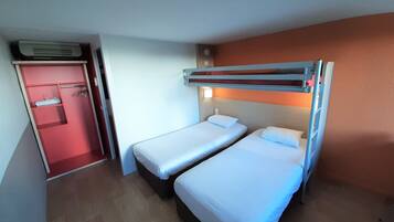 A compact hotel room with two single beds, a red door, and a built-in wardrobe.