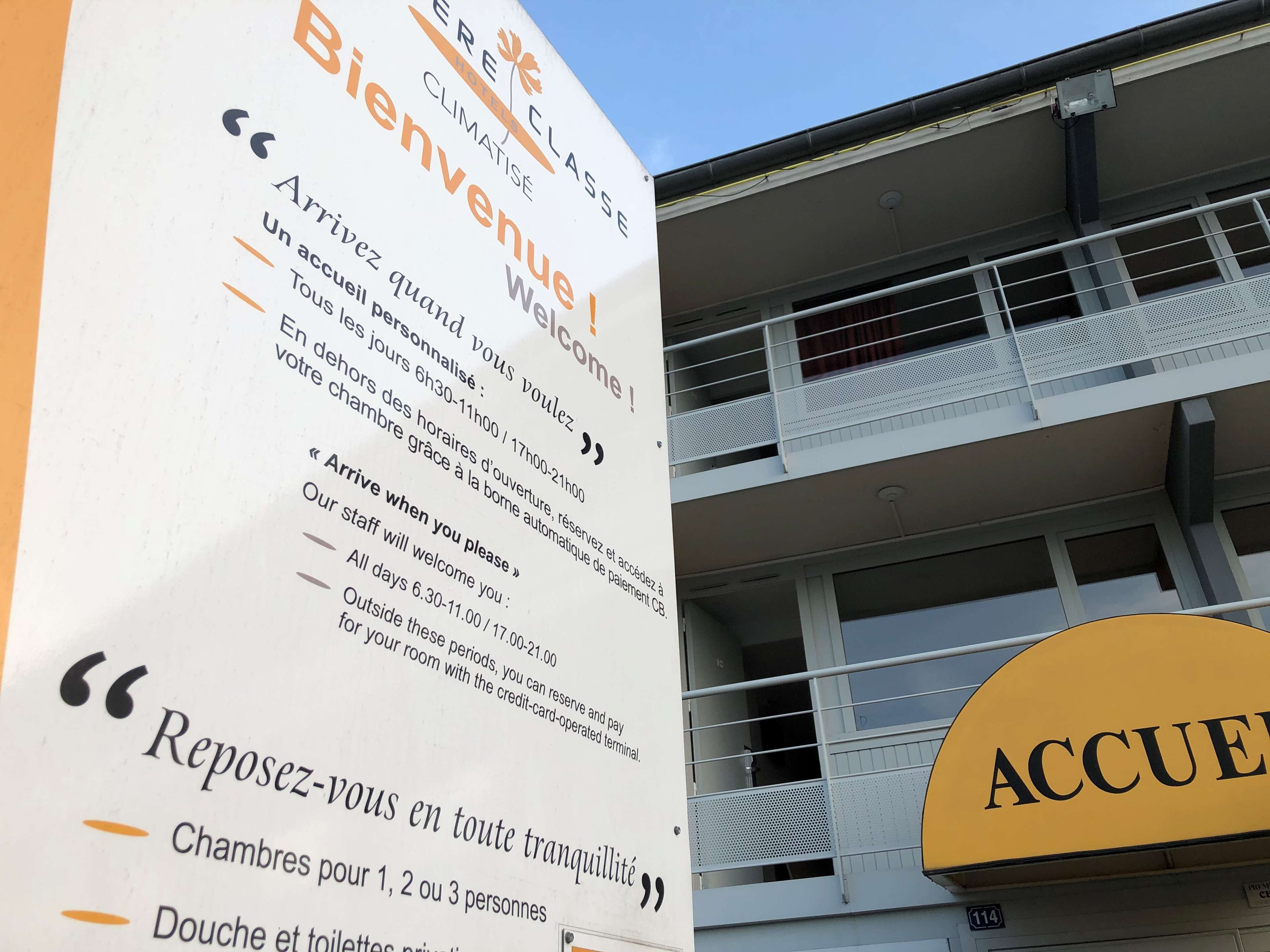 A hotel sign with "Bienvenue" and "Reposez-vous en toute tranquillité" indicating a welcoming message and rooms available for 1, 2, or 3 people.