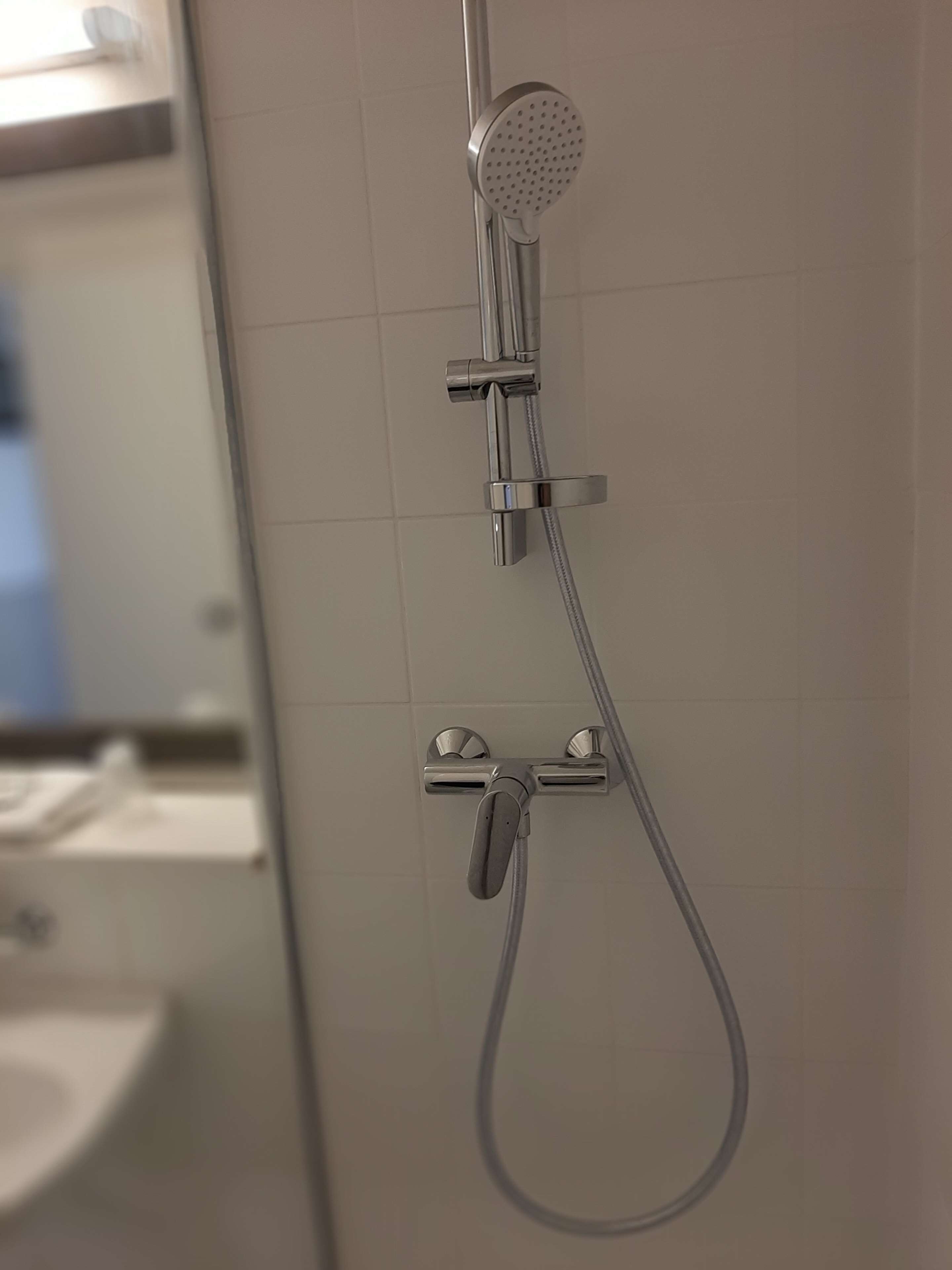 Una ducha con cabezal de ducha de mano y grifería empotrada.