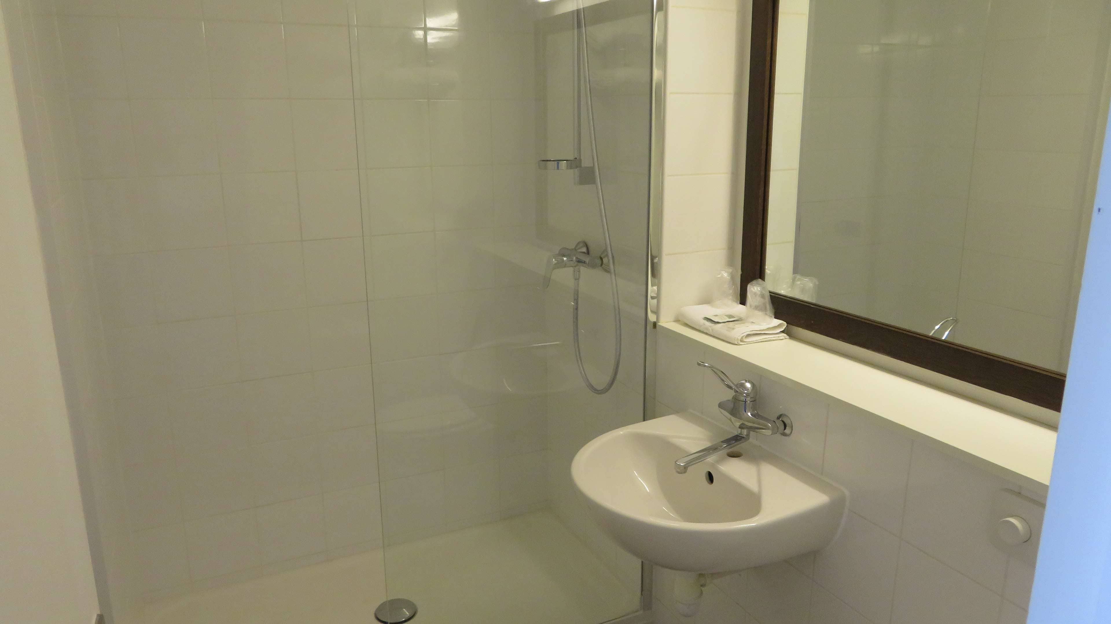 A bathroom with a glass-enclosed shower, a white sink, and a mirror above the sink.
