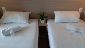 A hotel room with two beds, each with white linens and pillows, a small potted plant between the beds, and a wooden headboard. - Premiere Classe Mâcon Sud (Chaintre)
