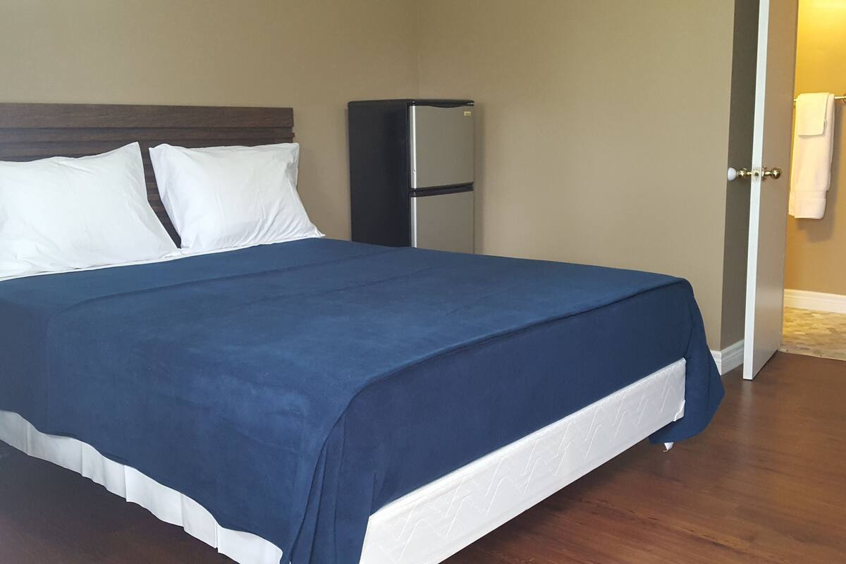 A hotel room with a bed, a wardrobe, and a door leading to a bathroom.