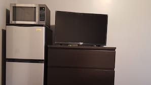 Uma cozinha compacta equipada com micro-ondas e uma televisão de tela plana sobre a geladeira.