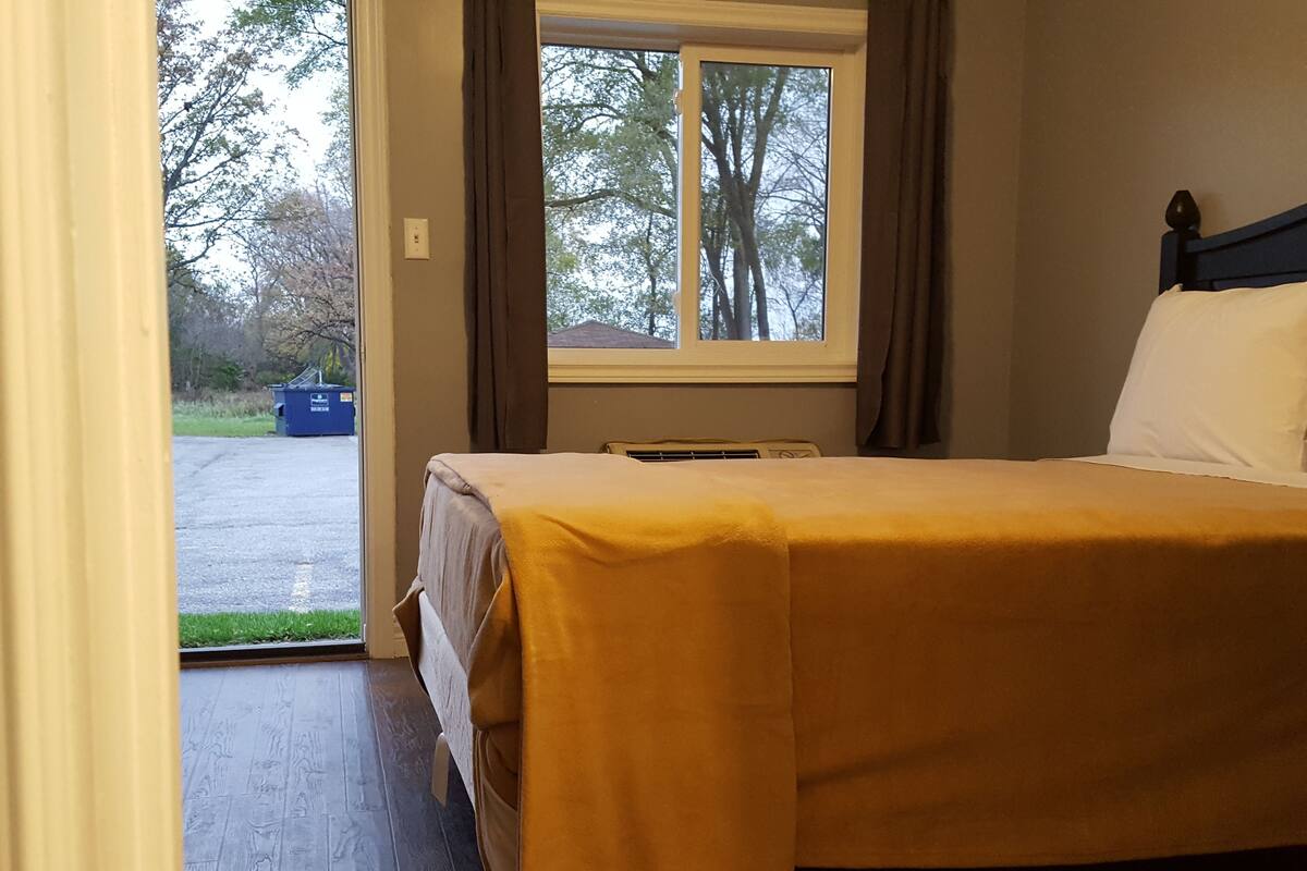 A room with a bed, a window, and a view of the outside.