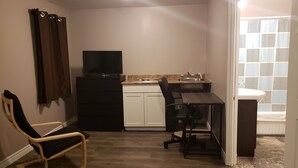Um espaço compacto com cozinha compacta, mesa de jantar, TV e uma cadeira.