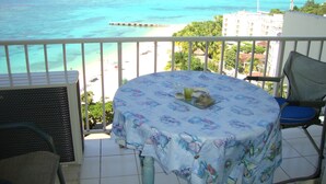 A balcony with a table and chairs, overlooking a beach and ocean. - Ocean Suite Beach Front at Mobay Club (Montego Bay)