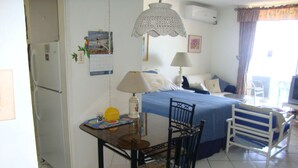A bedroom with a bed, a desk, a chair, a lamp, and a window with curtains. - Ocean Suite Beach Front at Mobay Club (Montego Bay)