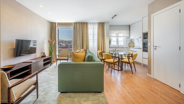 A modern living room with a sofa, TV, and dining area. - Casas do Porto - Ribeira Apartments (Porto)