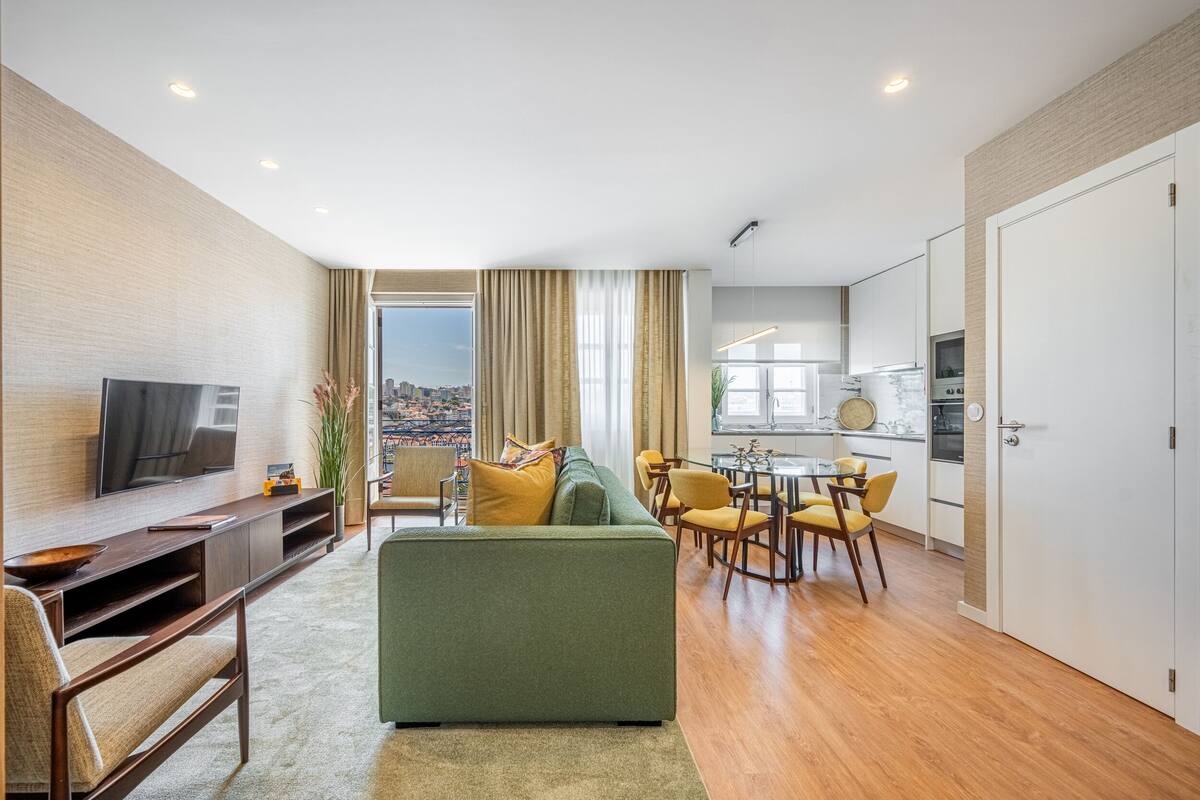 A modern living room with a sofa, TV, and dining area.
