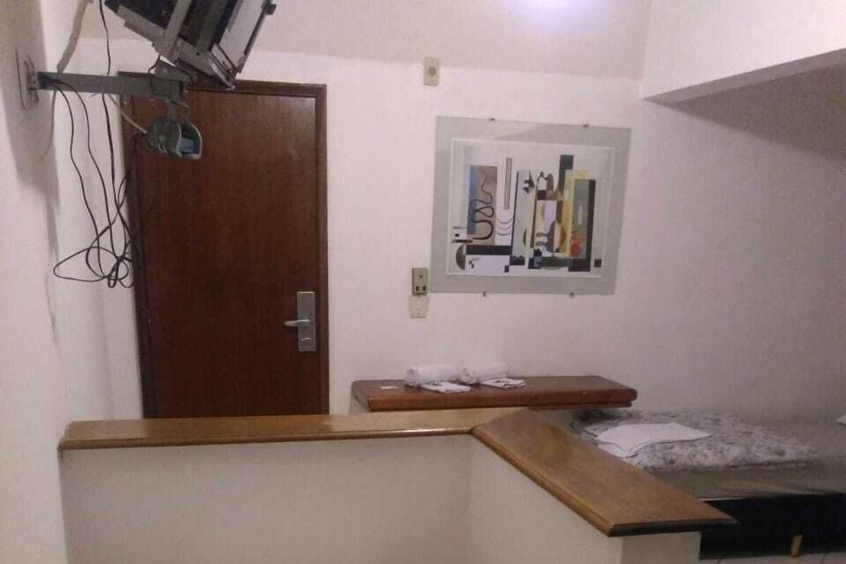 A small kitchenette with a refrigerator, a wooden counter, and a tiled floor.
