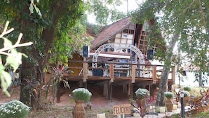 A rustic wooden structure with a balcony, surrounded by potted plants and a sign that reads "FELICIDADE". - Chalé Hotel (Bauru)