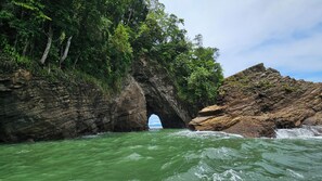 A natural rock arch formation with water flowing through it. - Vista Ballena (Bahía Ballena)