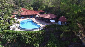 Un resort con una amplia piscina, zonas de estar al aire libre y un pabellón.