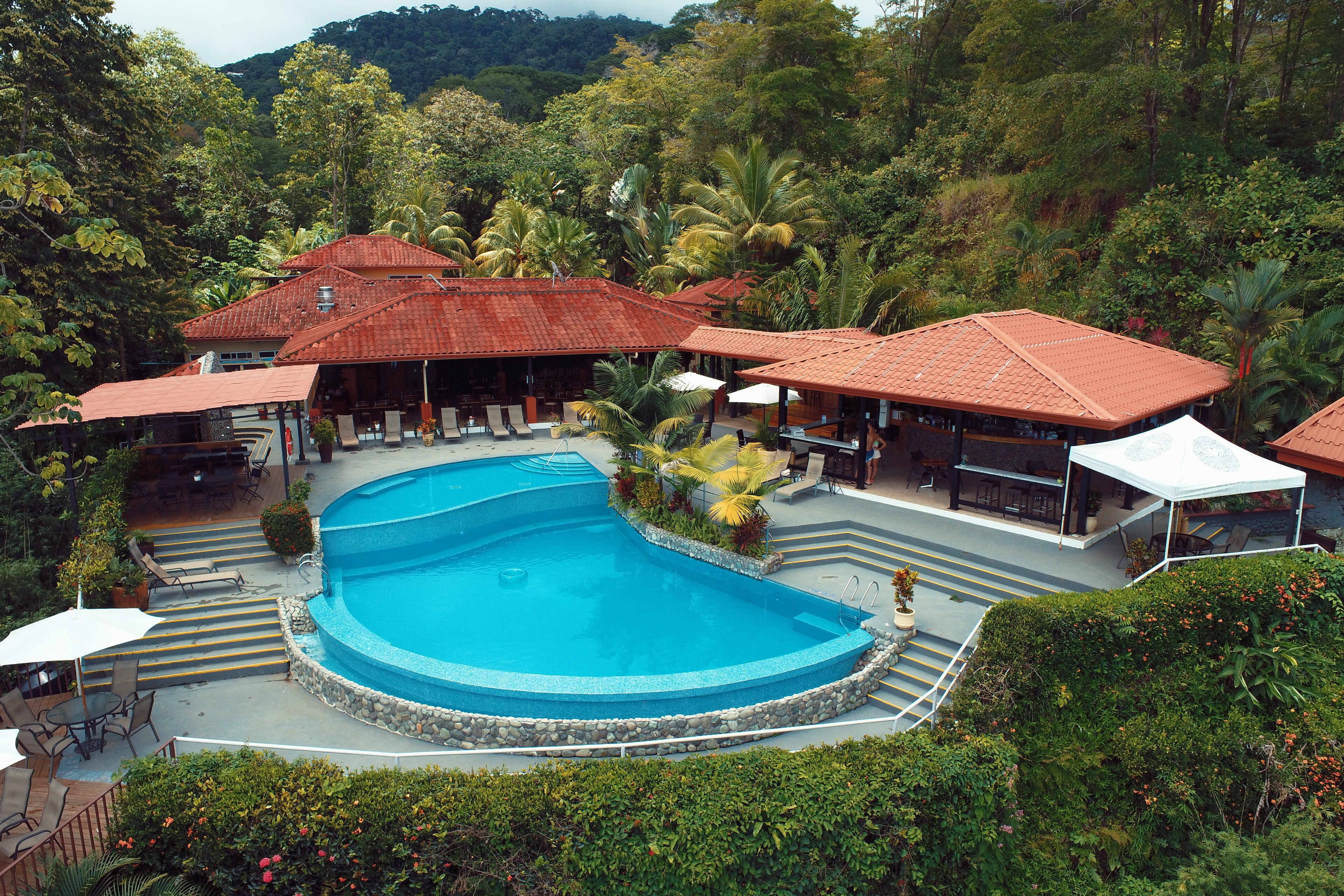 Un resort con piscina, zona de estar al aire libre y montañas al fondo.