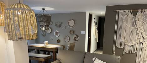 A modern living room with a grey sofa, wooden side table, and a dining area with a wooden table and chairs.