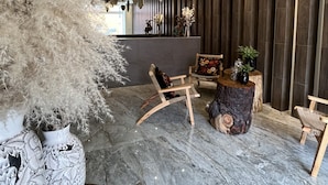 A modern interior with a chandelier, wooden chairs, a round wooden table, and decorative plants. - Zen Suites by Regente (Oaxaca)