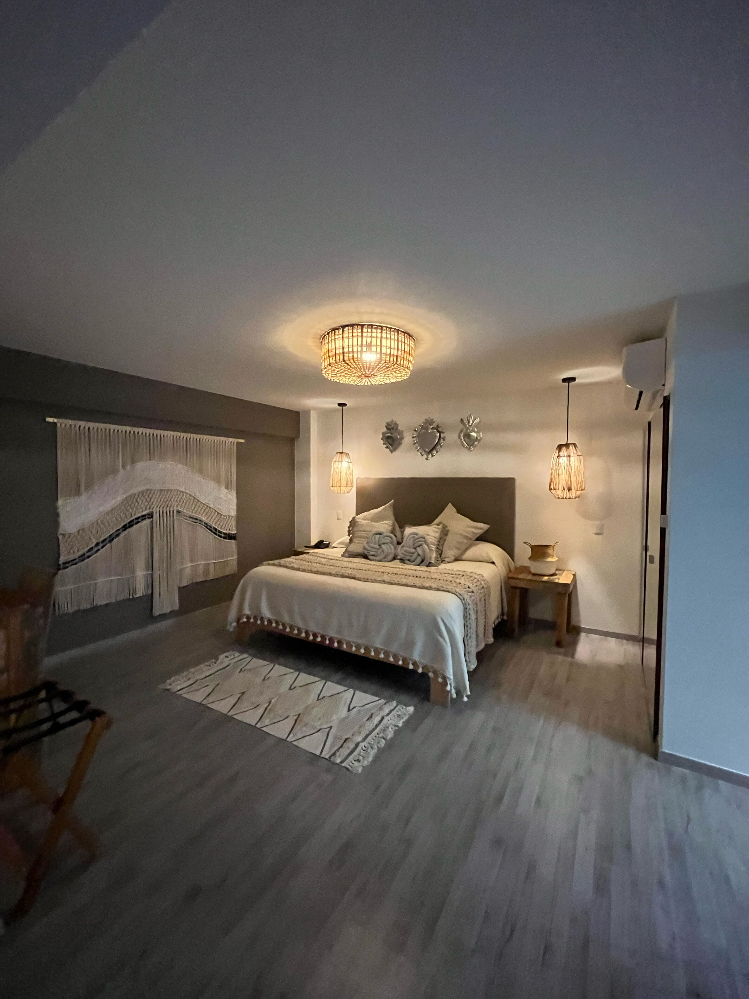 A modern bedroom with a large bed, a chandelier, and a small table with a lamp.