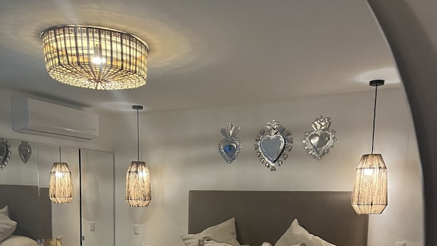 A modern bedroom with a large bed, two bedside tables, a wooden bench, and decorative heart-shaped mirrors on the wall. - Zen Suites by Regente (Oaxaca)