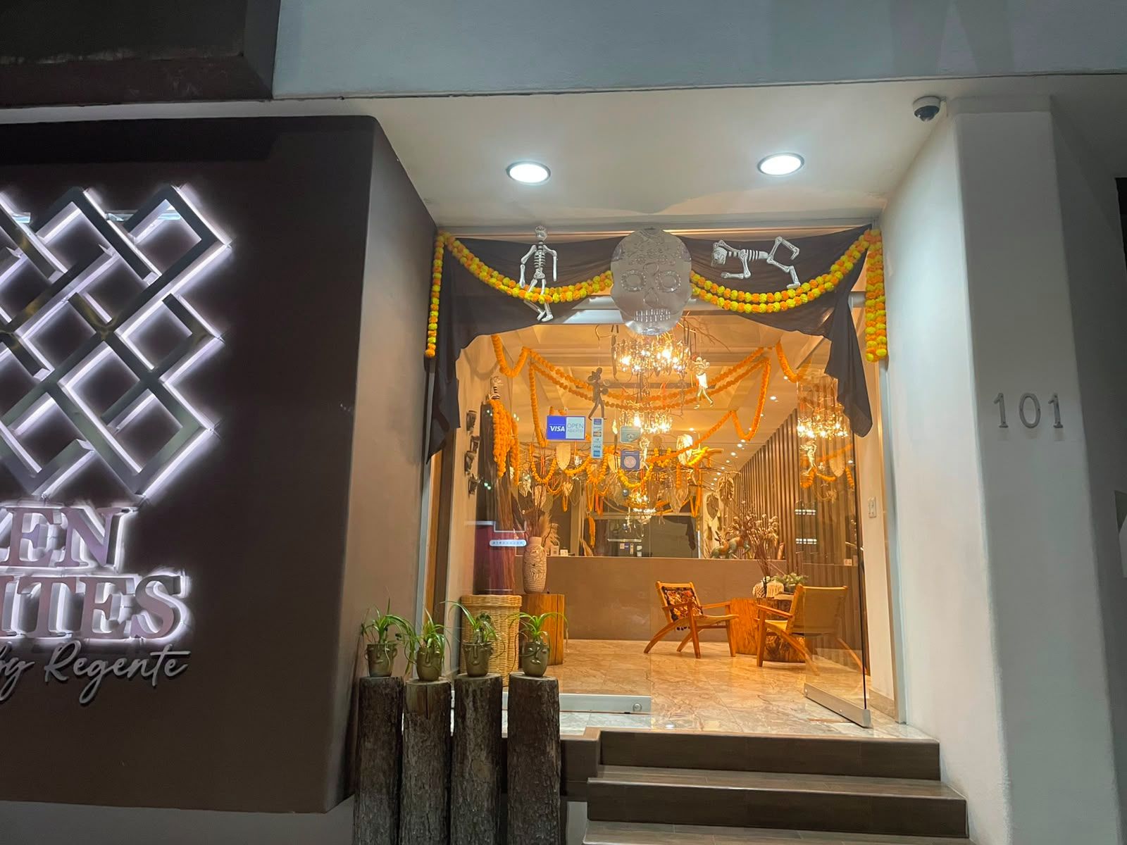 A storefront with a neon sign, a staircase leading to the entrance, and a display of furniture inside.
