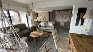 A modern living room with a grey sofa, wooden coffee table, and wicker chairs. - Zen Suites by Regente (Oaxaca)