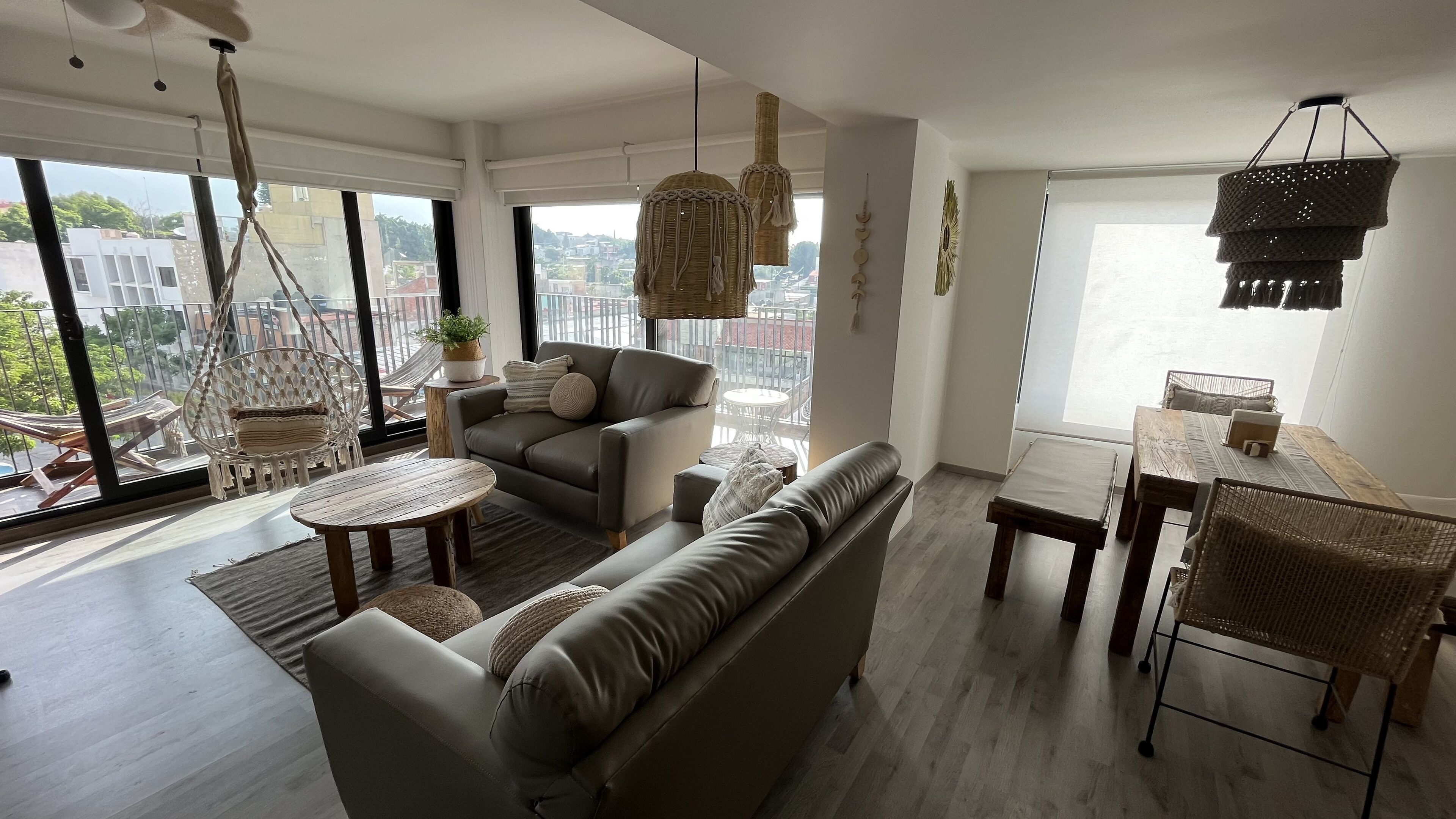 A spacious living area with a sofa, a dining table, and a hanging light fixture.