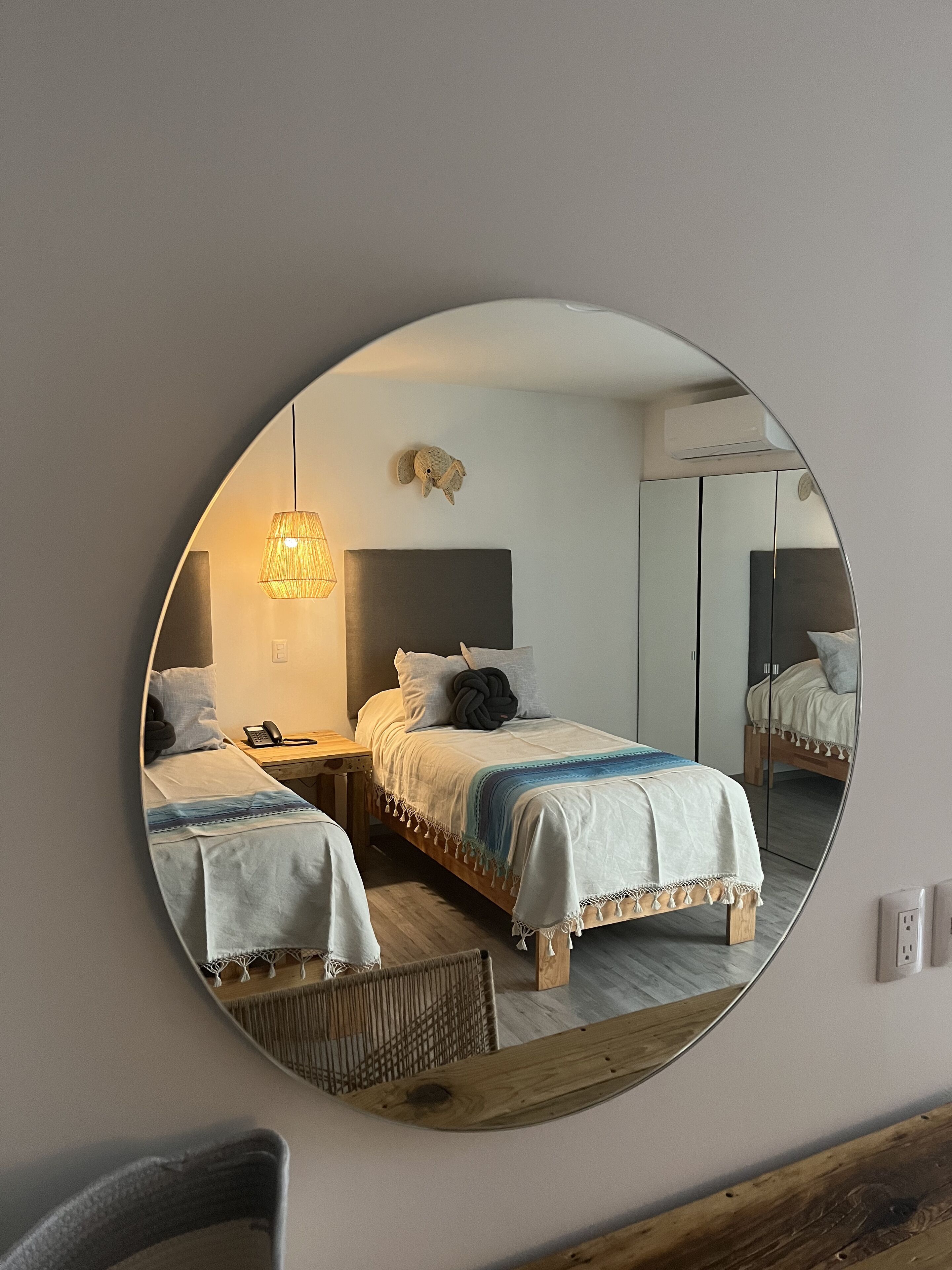 Ein Schlafzimmer mit zwei Betten, einem Spiegel, einer Lampe und einem kleinen dekorativen Gegenstand an der Wand.