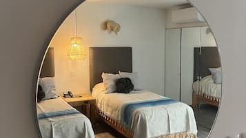 A bedroom with two beds, a mirror, a lamp, and a small decorative item on the wall.