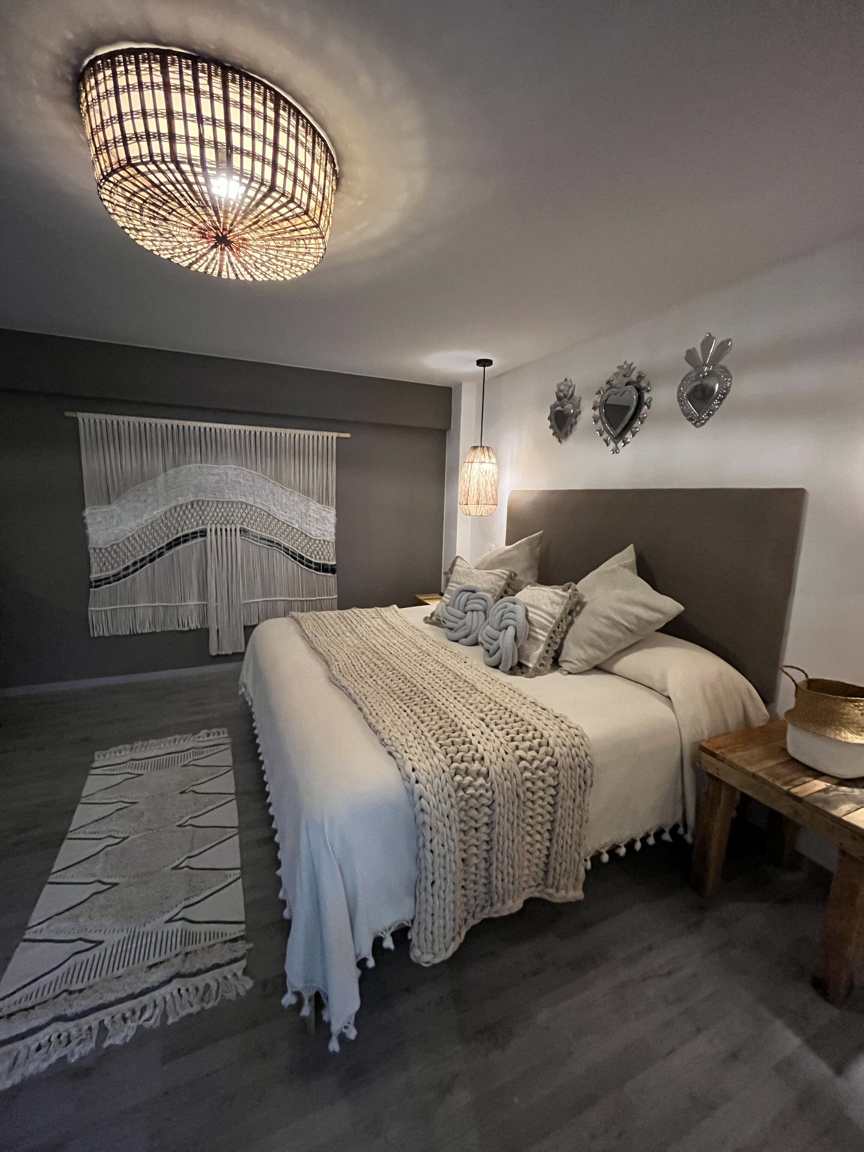 Une chambre moderne avec un grand lit, un luminaire suspendu et des œuvres d’art décoratives au mur.