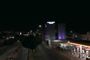 A hotel with a prominent sign, a gas station with a Shell logo, and a highway in the background. - Hoteles Unico Express (León)