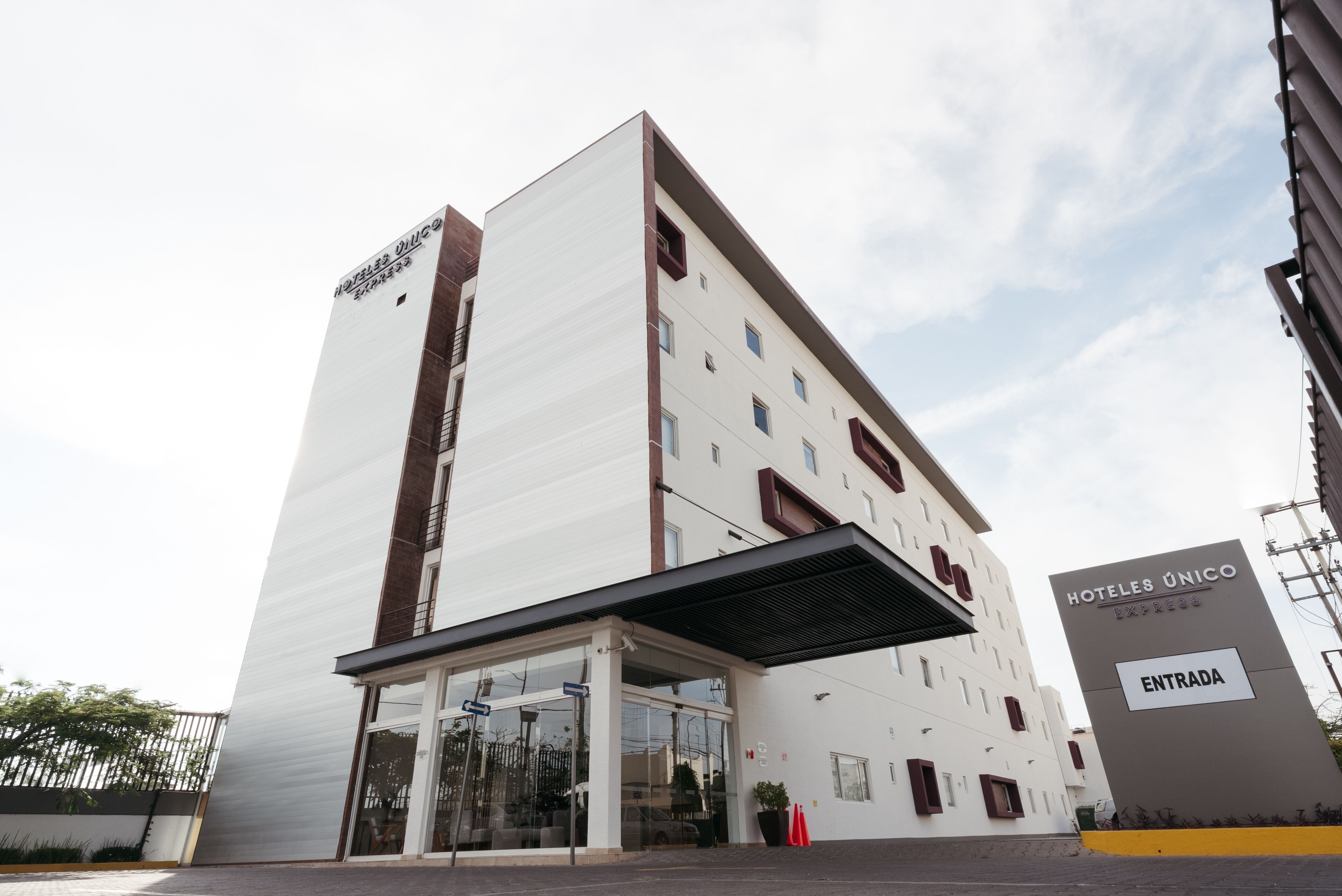 A modern hotel building with a prominent entrance and a sign indicating "HOTELES ÚNICO EXPRES".