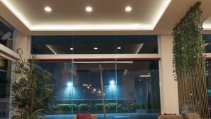 A modern lobby with a seating area, a large potted plant, and a view of the outside. - Hoteles Unico Express (León)