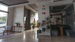 A modern lobby with a reception desk, seating area, potted plants, and a staircase. - Hoteles Unico Express (León)
