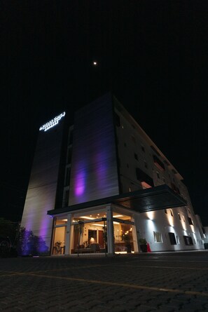 A hotel with a modern design, featuring a prominent sign and a well-lit entrance.