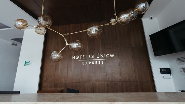 A reception area with a wooden wall and a sign that reads "HOTELES ÚNICO EXPRESS". - Hoteles Unico Express (León)