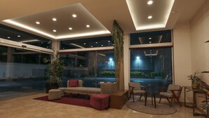 A modern lobby with a seating area, large windows, and a ceiling with recessed lighting. - Hoteles Unico Express (León)