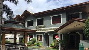 A two-story building with a covered patio area, outdoor seating, and a well-maintained garden. - The Gabriella B&B (Tagbilaran)