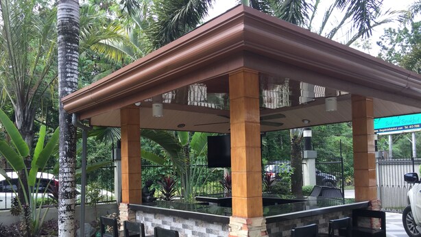 A covered outdoor bar area with a stone and brick column structure, black bar stools, and a glass-top counter. - The Gabriella B&B (Tagbilaran)
