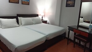 A hotel room with a double bed, a desk with a chair, a nightstand with a lamp, and two framed pictures on the wall. - The Gabriella B&B (Tagbilaran)