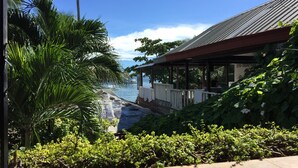 A view of a beach with a covered area and lush greenery.