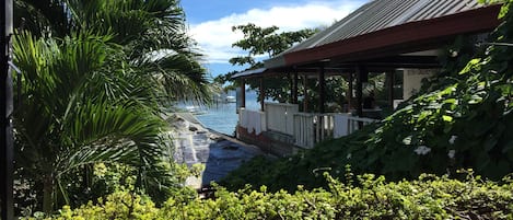 A view of a beach with a covered area and lush greenery.