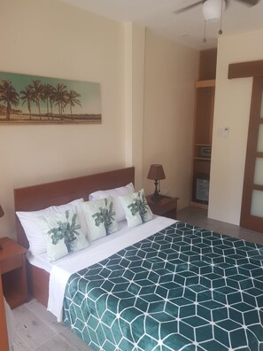 A bedroom with a bed, a nightstand, a lamp, a painting, and a wardrobe. - Hayahay Resort (Panglao)