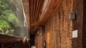 A narrow corridor with wooden beams and brick walls, leading to a wooden door at the end.