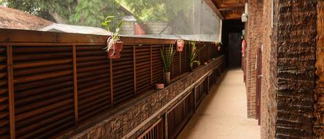 A corridor with wooden railings, potted plants, and a brick wall.
