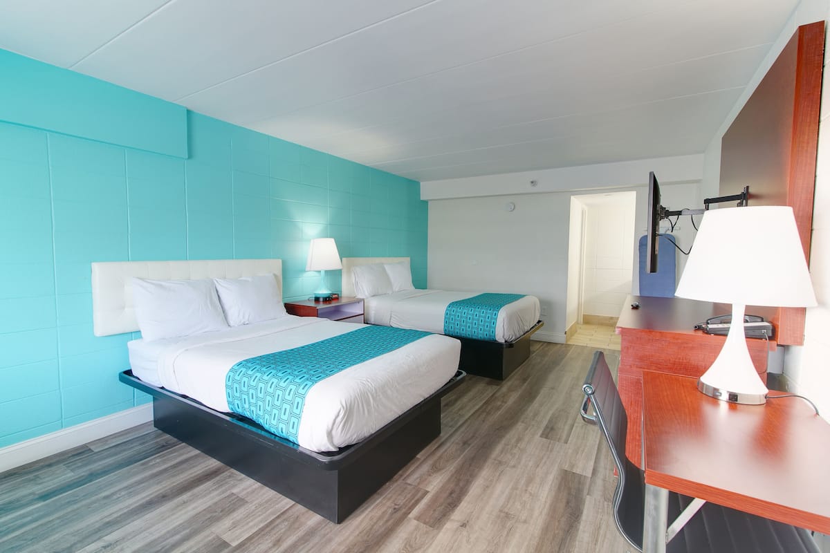 Une chambre d’hôtel avec un grand lit, un lit plus petit, un bureau et une chaise.