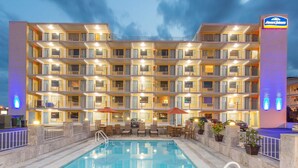 Ein mehrstöckiges Hotel mit Balkonen, einem Schwimmbad und Sitzgelegenheiten im Freien.