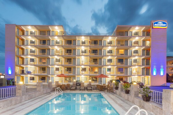 Un hôtel à plusieurs étages doté de balcons, d’une piscine et d’un espace extérieur aménagé pour s’asseoir.